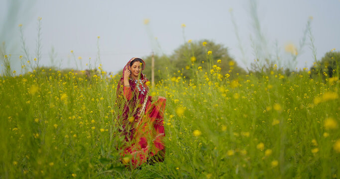 Indian happy adult gen x model woman lady wear red saree standing outdoor Asian relax female look candid do pose yellow flower in fresh air enjoy desi life