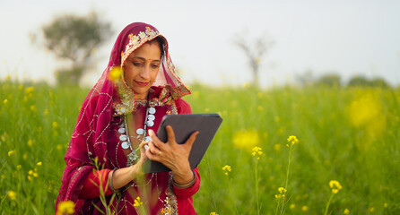 Indian village farmer woman lady wear red traditional saree standing outdoor farmland holding...