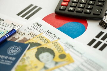 South Korean won money bills lies on table with pen, calculator, passport and tax forms