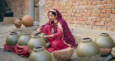 Indian village woman wear traditional saree sitting outdoor make hand made potters finishing...