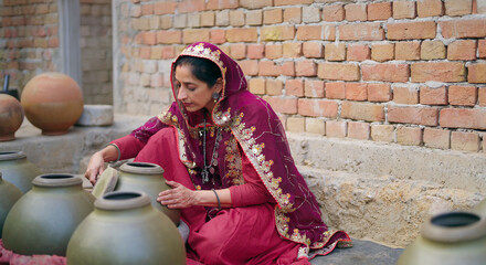 Indian village woman wear traditional saree sitting outdoor make hand made potters finishing...