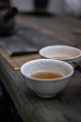 two white tea cups in wabi sabi style at chinese tea ceremony on wooden table, vertical photo with space for text