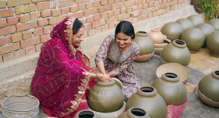 Indian mature adult woman lady mother with young teen middle age girl sitting home making hand made potters shape touches clay pots asian female art skill create pottery mud product outside house