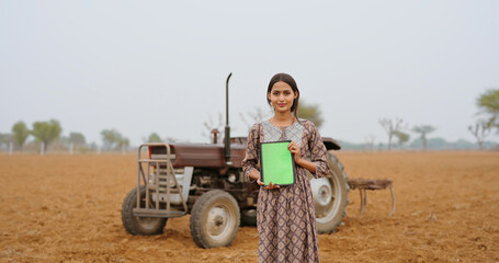 Indian young adult gen z farmer woman lady wear casual dress standing outdoor farmland hold green...