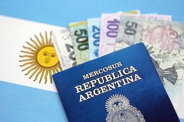 Argentine pesos money bills in big amount and passport lies on Argentina flag close up