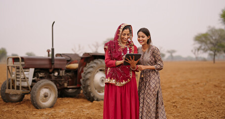 Indian asian villager farmer young adult woman lady wear red saree smiling outdoor hold tab device...