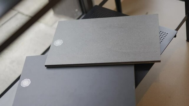 Two pieces of paper with a sticker on them. One is black and the other is gray