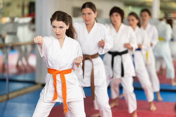 Female athletes standing in formation, kata starting position. Sportswomen studying and repeating sequence of punches and painful techniques in karate technique. Sports community..