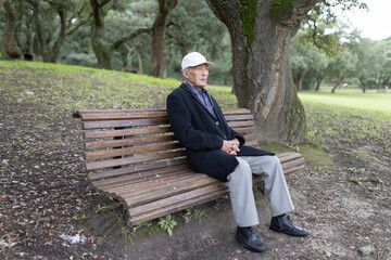 Fototapeta premium Senior man relaxing on park bench in autumn