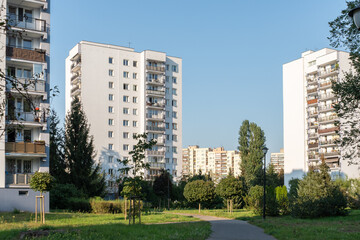A typical residential housing estate in a city dormitory district. The high-rise blocks of flats are surrounded by a large green park area with trees and a walking path.
