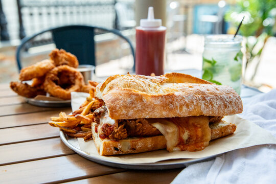 Chicken parmesan on crusty baguette french fries and onion rings  