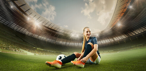 Hand made collage. Female footballer smiles confidently while tying shoes next to ball on bright field, stadium lights glowing above. 3D rendering stadium. Concept of sport, football, preparation © Lustre Art Group 