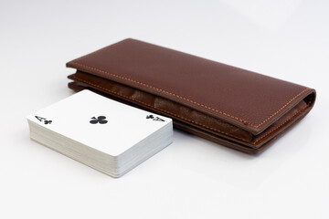 Playing cards deck next to leather wallet on white isolated background