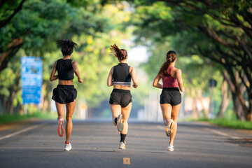 Three women are running down a road. One of them is wearing a black tank top. The other two are wearing black shorts