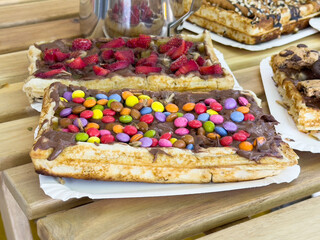 Delicious chocolate covered waffles with colorful toppings on wooden table