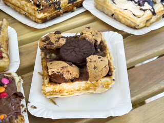 Delicious waffle with chocolate chip cookies and oreo topping on a paper plate