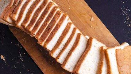 overhead shot of Freshly baked bread sliced into thin pieces kept on a wooden chopping board - Powered by Adobe