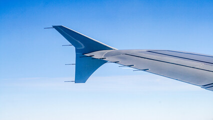 Airplane wing with a view of the blue sky from the window.