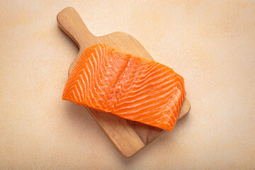 Fresh salmon fillet on wooden board, ready for delicious meal preparation and cooking. Healthy...