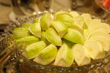 Guava slices plate rotating plate of guava with a whole guava and leaves in the center, surrounded by neatly arranged sliced pieces