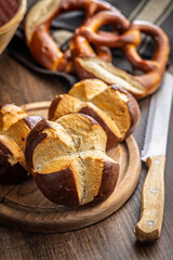 Crunchy bavarian buns on cutting board on wooden table.