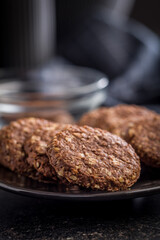 Sweet oatmeal cookies on plate on black table.