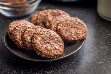 Sweet oatmeal cookies on plate on black table.