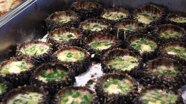 Sea urchins sashimi fresh open and ready to eat on ice in Kyoto fish market. Close up of delicious traditional japanese uni seafood at stall for sale. Japan food travel and cuisine store street 