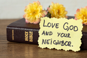 Love God and your neighbor, inspirational handwritten quote with holy bible book. Close-up....