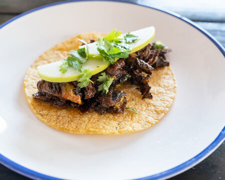 Seasoned beef taco on a corn shell with cilantro and green apple 