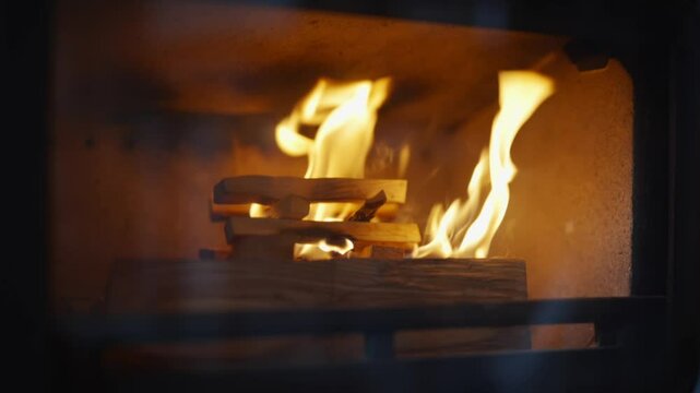 A fire is burning in a fireplace, with the flames reaching up to the top of the firebox