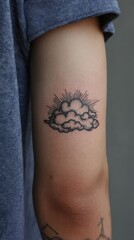Minimalist cloud tattoo on arm of young caucasian male with sunburst design