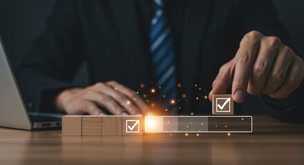 A person typing on a laptop with digital security icons floating around the screen on a wooden desk