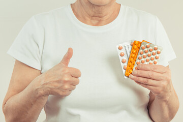 Elderly senior woman with tablets or supplements in hand. Treatment or strengthening immunity in old age
