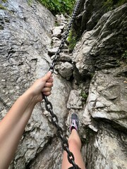 Climbing a rocky path with a chain in a natural landscape during daylight hours