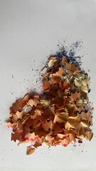 Shavings of colored pencils create a vibrant display on a white surface showcasing artistic creativity and playfulness