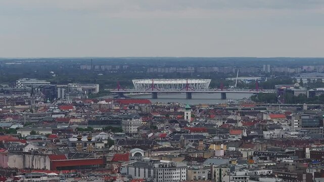 Aerial view of Budapest, Hungary, featuring Puskas Arena, urban architecture, and a slow pan revealing greenery under an overcast sky.