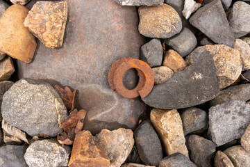 Gravel in a railway track, unregularly shaped. An old rusty steel tension ring lying in the middle....