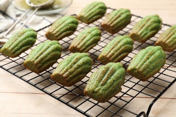 Tasty matcha madeleine cakes on light wooden table, closeup