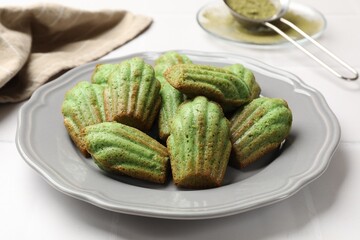 Tasty matcha madeleine cakes on white tiled table, closeup