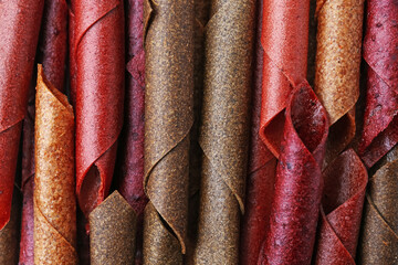 Delicious fruit leather rolls as background, top view