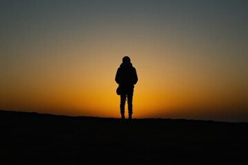 Silhouette of person standing in golden sunset light