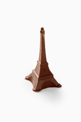 Chocolate eiffel tower sparkling with gold dust on white background