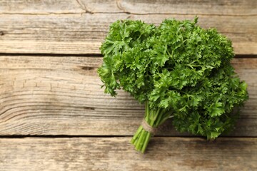 Bunch of fresh parsley on wooden table, top view. Space for text