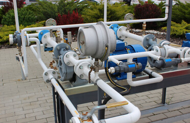 Compressors and shut-off valves with gas pressure sensors on pipes near an underground storage tank at gas station