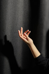 Woman hand reaching for light against dark background with shadow