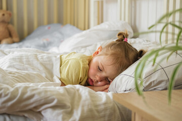 Peaceful adorable baby sleeping on a bed at home. Slumbering little child. Two years old girl sleeps peaceful at domestic room interior background. Serene dream. Cute face close up. Deep kid slumber