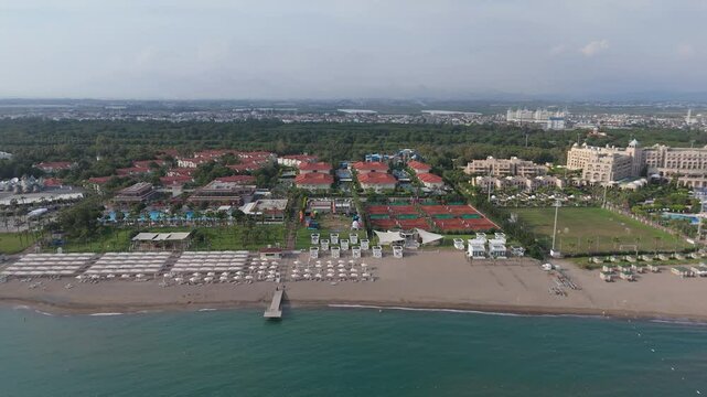 Aerial View 4K Majestic Shores of Belek Beachfront Paradise. Sandy Beaches of the Mediterranean Sea. Belek Holiday Complex With Five Star Hotels. Beach, Sea, Water Sports, Aquapark, Parasailing