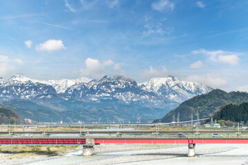 Panoramic view of Himakawa River in Itoigawa, Niigata, Japan, with bridges and snow-covered mountains in the background
