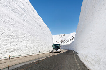 Fototapeta premium Bus between high Snow Wall or Snow Corridor in Tateyama Mountain Range of Northern Japan Alps, 2450 meters above sea level along Tateyama Kurobe Alpine Route